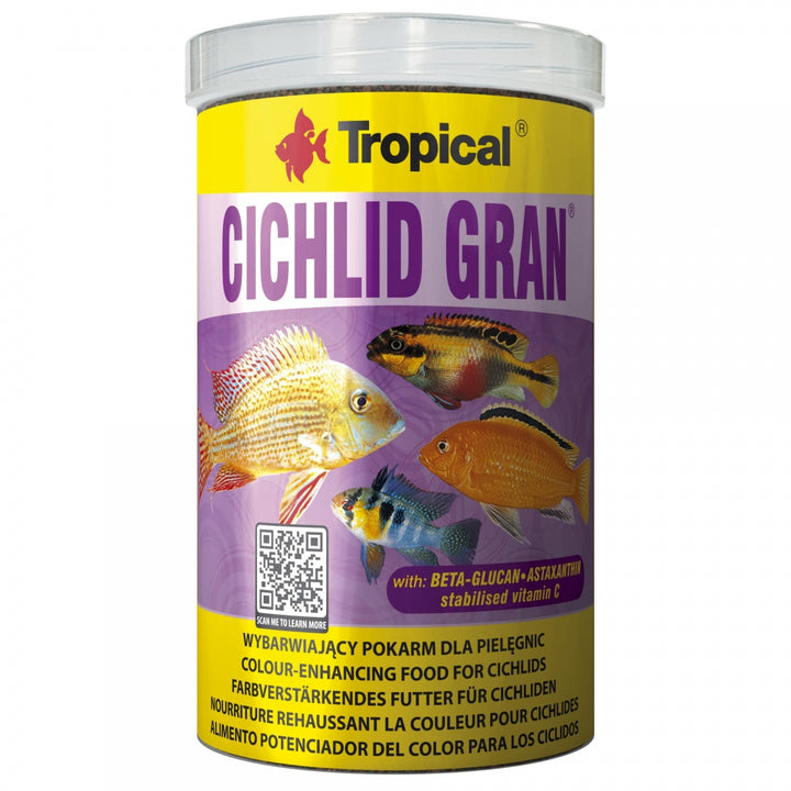 A cylindrical plastic jar of Tropical Cichlid Gran color-enhancing fish food, featuring a yellow and purple label with illustrations of various cichlid fish.